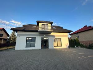 a white house with a balcony on top of it at Apartament Oksford 3 in Okszów