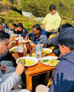 un grupo de personas sentadas en una mesa comiendo comida en Sindhu Organic Agro And Farmstay, en Mahānkāl