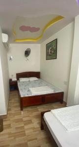 1 dormitorio con 2 camas y una pintura amarilla en la pared en Nhà nghỉ Nam Anh, en Can Tho