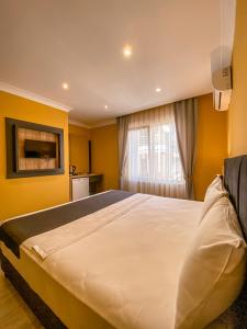 a bedroom with a large bed with yellow walls at Roy Otel Akçay in Akcay