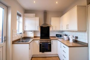 een keuken met witte kasten en een wastafel bij Charming Middlesbrough Home in Middlesbrough