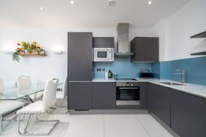 a kitchen with gray cabinets and a table and chairs at Fantastic flat near Tower Bridge in London