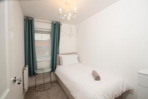 a bedroom with a white bed and a chandelier at Cosy Home with Garden in a Picturesque Village in Hull