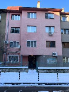 a pink building with snow in front of it at Eternity Apartment: Award-Winning Design in the Heart of the City Center in Sofia