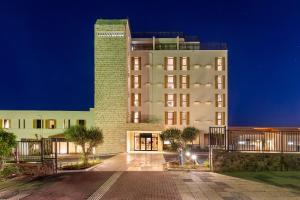 a large white building with a tall tower at night at Roxon Desert Arad in Arad