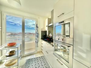 een keuken met witte kasten en een groot raam bij Bristol by Welcome to Cannes in Cannes