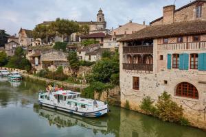a boat floating down a river next to buildings at Pénichettes itinérantes sans permis - Locaboat in Lattes