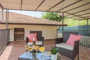 een patio met 2 stoelen en een tafel met wijnglazen bij Maison Tuscany Jacuzzi, Netlflix and Free Parking near Forte dei Marmi in Carrara
