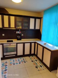 a kitchen with wooden cabinets and blue curtains at Апартамент ВалАнди in Samokov
