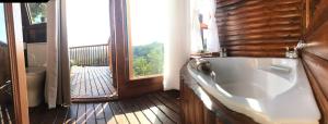 ein Bad mit einer großen Badewanne in einem Zimmer mit einem Balkon in der Unterkunft Teniqua Treetops in Sedgefield