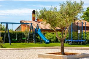 een speeltuin met een boom en een glijbaan bij Villa Bella Vita by Istrabook in Rebići