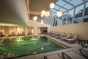 バート・ホーフガシュタインにあるHotel Norica - Thermenhotels Gastein mit dem Bademantel direkt in die Thermeの椅子とプールが備わる建物内のプール