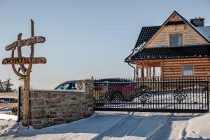 un cartel frente a una casa de madera en la nieve en HRYCÓWKA Domki z Widokiem, en Grywałd