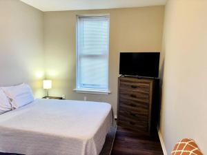 1 dormitorio con 1 cama y TV de pantalla plana en Two Bedroom Queen Bed Suite, en Harrisburg