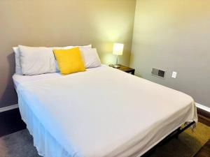 1 dormitorio con 1 cama blanca grande con almohada amarilla en Two Bedroom Queen Bed Suite, en Harrisburg