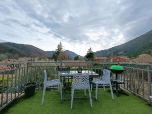 a table and chairs on a balcony with mountains at Appartement design avec piscine in Digne-les-Bains