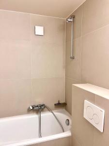 La salle de bains est pourvue d'une baignoire blanche et d'une douche. dans l'établissement Luxury Studio Near UN & Train Station, à Genève