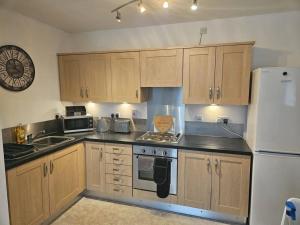 a kitchen with wooden cabinets and a white refrigerator at Leopard in Dutton Warrington in Warrington