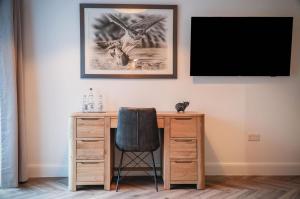 a desk with a chair and a television on a wall at Suite 4 - Sleeping Giant Hotel - Pen Y Cae Inn in Brecon