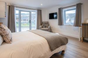 a bedroom with a bed and a chair and windows at Suite 2 - Sleeping Giant Hotel - Pen Y Cae Inn in Brecon