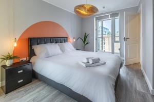 a bedroom with a large white bed and a large window at Lovely 3BR Penthouse wBalconies, Poplar, 2min DLR in London