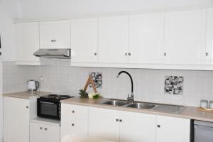 a kitchen with white cabinets and a sink at Amelia in Kavoúsion