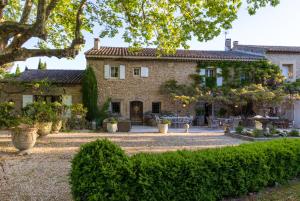 uma grande casa de pedra com um jardim em frente em Le Clos de Lucie em Lagnes