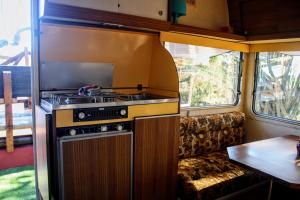 - Cocina en una cabaña con fogones y sofá en Caravana Vintage Star vistas Mar y Montaña, en Nàquera