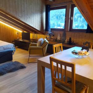 a living room with a table and a room with a couch at Mansarda delle Dolomiti nuovissimo appartamento in Madonna di Campiglio