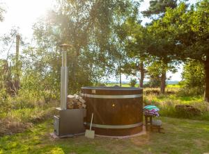 a hot tub in a field with a bench and trees at Orion 4-Person Lotus Belle Tent in Ross on Wye