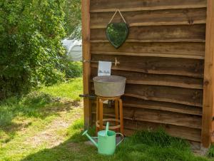 a bucket on a stool next to a wooden wall at Orion 4-Person Lotus Belle Tent in Ross on Wye