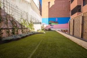 un patio con césped y un mural en el lateral de un edificio en TX Matadero en Madrid