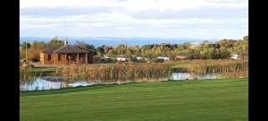 a house on a golf course next to a pond at The Chill Out at Seton Sands in Port Seton