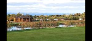 una casa en un campo de golf junto a un estanque en The Chill Out at Seton Sands, en Port Seton