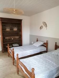 a bedroom with two beds and a chandelier at La Maison des Rosiers in Manhac