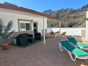 eine Terrasse mit Liegestühlen und einem Tisch mit einem Berg in der Unterkunft Apartamentos Casa Mime in Mogán