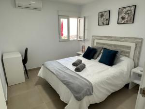 a bedroom with a large white bed with blue pillows at Apartamentos Casa Mime in Mogán +22 photos