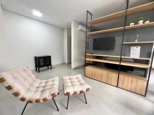 a living room with two chairs and a television at SoHo Bosque - Studios & Lofts in Presidente Prudente