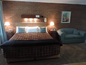 a bedroom with a bed and a couch and a chair at Greenacres Motel in Corowa