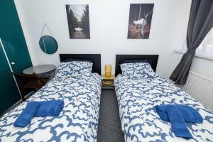 two beds in a bedroom with blue pillows and a table at Rooms Close to Canary Wharf in London