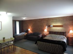 um quarto com uma cama e uma sala de estar com uma parede de tijolos em Greenacres Motel em Corowa
