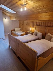 two beds in a room with wooden walls at Huberhof, Mettenham in Schleching