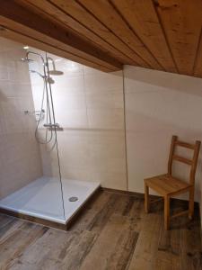 a shower with a glass door next to a chair at Huberhof, Mettenham in Schleching