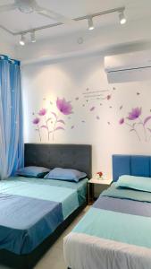 two beds in a room with purple flowers on the wall at Ocean Home@Urban Suites@12 Pax in Jelutong
