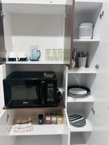 a kitchen with a black microwave on white shelves at CASA SHILCAYO Habitaciones Vacacionales in Tarapoto