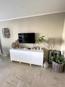 ein Wohnzimmer mit einem TV und einem weißen Schrank in der Unterkunft Joli studio près des plages in Mandelieu-la-Napoule