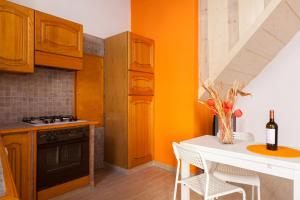 ローマにあるBoccanera a Trastevere Holiday Apartmentのオレンジの壁のキッチン(白いテーブル付)