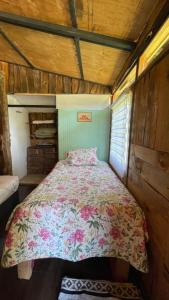 1 dormitorio con 1 cama con colcha de flores en Cabaña de la nona, en Futaleufú