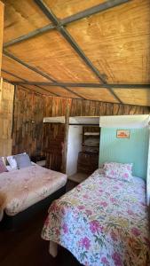 a bedroom with two beds and a wooden ceiling at Cabaña de la nona in Futaleufú