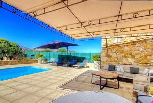 eine Terrasse mit einem Pool, Stühlen und einem Sonnenschirm in der Unterkunft Villa terranga in Calenzana